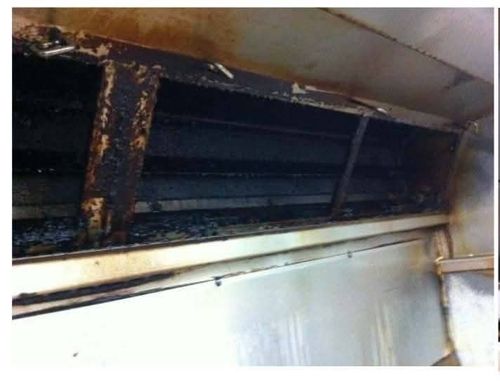 Commercial kitchen exhaust canopy with heavy grease build-up before cleaning